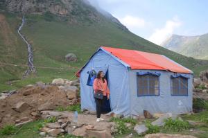 a woman standing in front of a blue and red tent at Outdoor Adventures Camp Ratti Gali Lake in Shardi