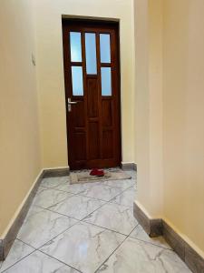 an empty room with a wooden door and a tile floor at Kili Vista Homes in Moshi