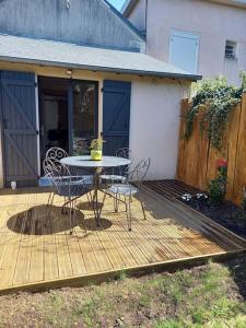 a wooden deck with a table and chairs on it at La petite longère La mercerie in Bourges