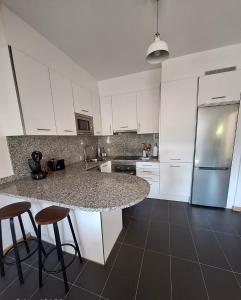 a kitchen with white cabinets and a marble counter top at Aldea Bricia 12 in Posada de Llanes +10 photos