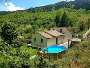 a house with a swimming pool next to a mountain at B&B Maison Colette Valgorge in Valgorge