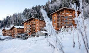 a group of buildings in the snow with trees at MGM Hôtels & Résidences - Hôtel Laska in Les Contamines-Montjoie