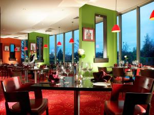 a restaurant with a table and chairs and windows at Carlton Hotel Blanchardstown in Blanchardstown