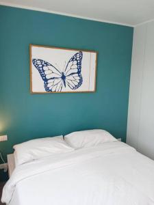 a butterfly picture on a blue wall above a bed at 2BR Aparment Near The Beach T2-717 in Phuket Town