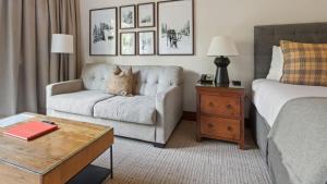 a hotel room with a bed and a couch and a chair at 1125 Lodge At Spruce Peak Ski In Ski In Ski Out King Studio By Stowe Mountain Rentals in Stowe +10 photos
