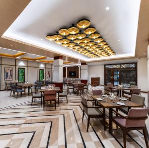 a restaurant with tables and chairs and a large chandelier at Charmwood Hotel in Leh