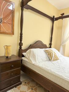 Un dormitorio con una cama con dosel y una cómoda de madera. en Cajigal Farmhouse - high speed converge internet and AC in 2 bedrooms, en Badoc