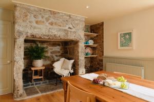 a living room with a stone fireplace and a wooden table at Bosistow Farmhouse in Penzance