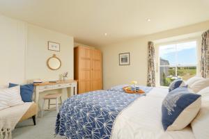 a bedroom with a bed and a desk and a window at Bosistow Farmhouse in Penzance