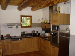 a kitchen with wooden cabinets and a stainless steel refrigerator at Grand chalet proche St Lary Soulan - tout inclus wifi linge et ménage in Aragnouet +9 photos