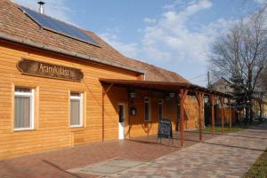 a wooden building with a sign on the side of it at Aranykalász Panzió in Szentes