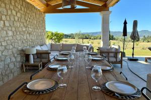 a wooden table with wine glasses on a patio at LE Mas Jas magnificent Mas Provençal - Lauris in Lauris