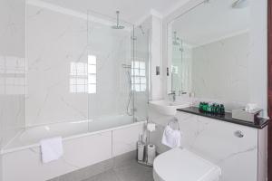 a white bathroom with a shower and a toilet and a sink at Gem Fitzrovia Hotel in London