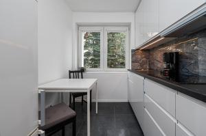 a white kitchen with a table and a window at Apartament Emily Brzeźno in Zaspa +21 photos