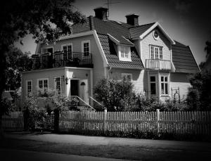 a black and white photo of a house with a fence at Konstnärsvåningen i Villa Sol in Borgholm