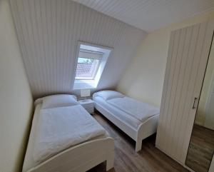 Un dormitorio pequeño con dos camas y una ventana. en Küstenglück Sylt D1, en Westerland