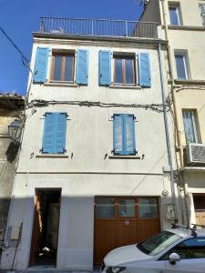 a building with blue shuttered windows and a car parked in front at Appartement Terrasse sur le port in La Seyne-sur-Mer