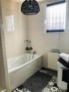 a bathroom with a bath tub and a window at Espace deux chambres et sanitaires in Puilboreau