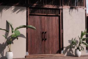 a wooden door of a building with two potted plants at UNÚ Beach Hotel in Palomino