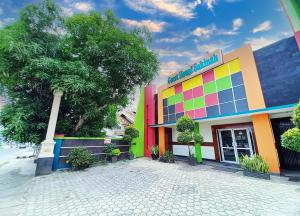 MetroGuest House Syariah GS Sakinah, Kota Metro的一座彩虹色的建筑,前面有一棵树