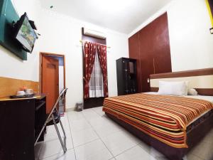 MetroGuest House Syariah GS Sakinah, Kota Metro的一间带床和书桌的酒店房间和一张床 sidx sidx