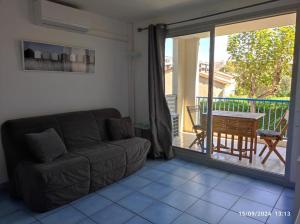 a living room with a couch and a table and a balcony at Studio cabine tout équipé in Le Lavandou