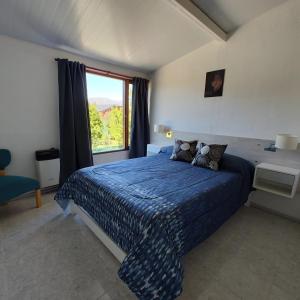 a bedroom with a large blue bed with a window at Sol de montaña, Bariloche. in San Carlos de Bariloche