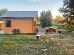 a small cabin with a deck and benches in a field at Rāznas ezera namiņš D1 ar elektrisko apkuri in Ragi +27 photos