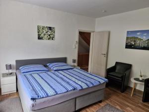 a bedroom with a bed with blue sheets and a chair at Ferienhaus Heimes in Klotten