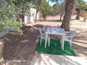 a table and two chairs sitting next to a tree at Maison la rose 2 chambres in Mezraya +2 photos