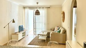 a living room with a couch and a tv at Bohemian Dreams Los Abrigos by Deihu Experiences in Granadilla de Abona