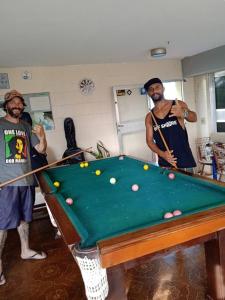 two men playing a game of pool in a room at Saqua Beach Hostel in Saquarema
