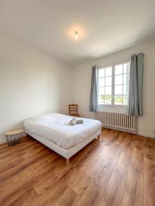 a white bedroom with a bed and a large window at Maison Cosy avec Jardin et Cheminée sur Vichy in Creuzier-le-Vieux