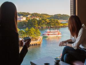 two women looking out a window at a boat in the water at View Hotel Iki in Iki