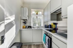 a kitchen with white cabinets and a sink at Central Worthing apartment in Worthing