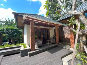 a patio of a house with a wooden deck at Riverside Villa Tanah Lot by Smart Digital in Munggu
