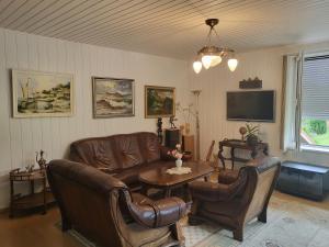 a living room with leather furniture and a tv at House Violeta in Nida