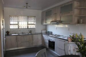a kitchen with wooden cabinets and a stove top oven at Hidden Gem in Bloemfontein +8 photos