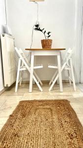 a dining room table with two white chairs and a rug at Central Comfort Guesthouse in Larisa +2 photos