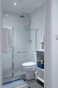 a white bathroom with a toilet and a shower at Apartamento simples e simpático in Horta