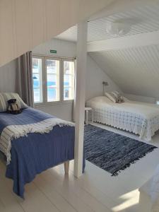a white bedroom with two beds and a blue rug at Forest Ranger's House, Authentic Lappish atmosphere in Äkäslompolo
