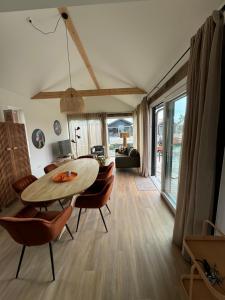 una sala de estar con una mesa y sillas en La Casita, Luxe Chalet Aan Het Water met Airco, en Anjum