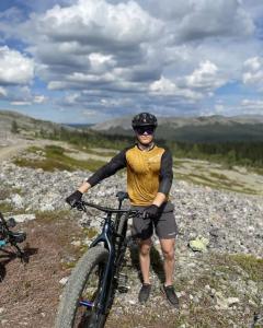 a man standing next to a bike on a hill at Forest Ranger's House, Authentic Lappish atmosphere in Äkäslompolo