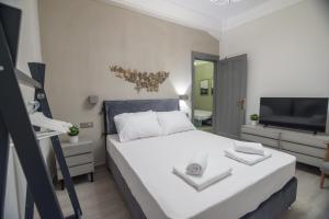 a bedroom with a white bed and a television at To Spitaki in Thessaloniki