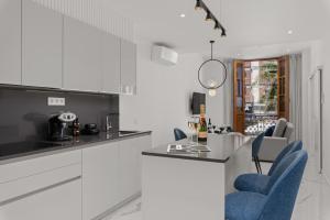 eine weiße Küche mit blauen Stühlen und einer Theke in der Unterkunft 7 Luxury Suites By KARAT in Santa Cruz de Tenerife