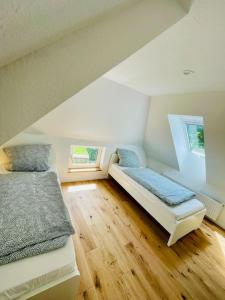 a attic room with two beds and two windows at Ferienhaus Butjadingen - Haus Burhave in Butjadingen