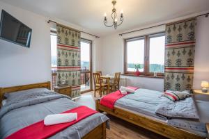 a bedroom with two beds and a table and chairs at Gościna Na Wierchu Murzasichle in Murzasichle