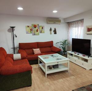 a living room with a red couch and a tv at El Arco de la Malena 2 in Siles