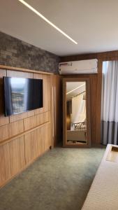 a room with a flat screen tv and a bedroom at Vista Azul Apart Hotel - Vista Pedra Azul in Pedra Azul