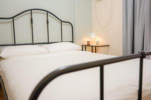 een slaapkamer met een wit bed met een metalen frame bij Alea Residences in Manilla +37 foto's